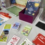 Tauschaktion Schulsachen: auf einem Tisch ausgebreitet liegen verschiedene Hefte, Spiele und Pläne