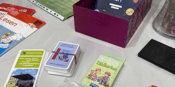 Tauschaktion Schulsachen: auf einem Tisch ausgebreitet liegen verschiedene Hefte, Spiele und Pläne