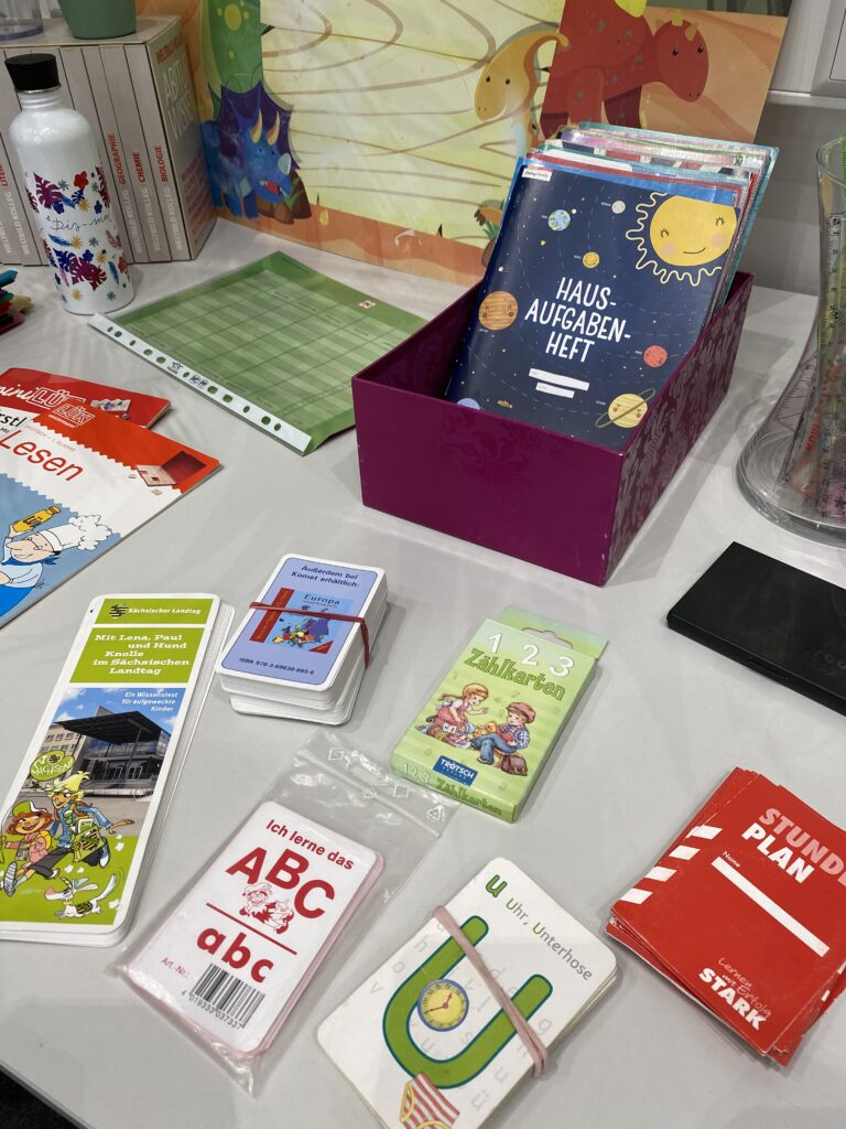 Tauschaktion Schulsachen: auf einem Tisch ausgebreitet liegen verschiedene Hefte, Spiele und Pläne